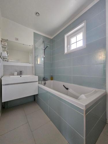 uma casa de banho com uma banheira, um lavatório e um espelho. em La Bretèche em Saint-Martin-le-Beau