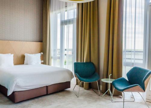 アムステルダムにあるアマディ パノラマ ホテルのベッド1台と椅子2脚が備わるホテルルームです。