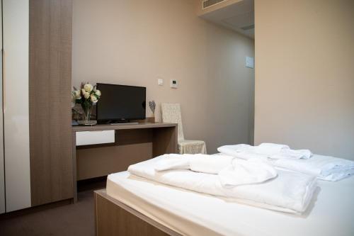 a bedroom with a bed with white sheets and a tv at Hotel Narenta in Metković