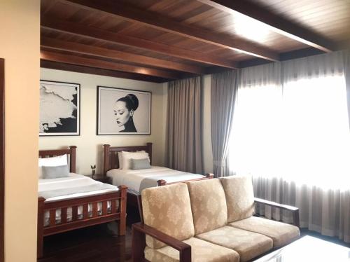 a bedroom with two beds and a couch and a window at Athena Hotel in Pakse