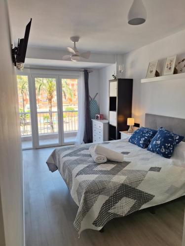 ein Schlafzimmer mit einem Bett mit blauen Kissen und einem Fenster in der Unterkunft Alicante El Campello 1º línea de playa in El Campello