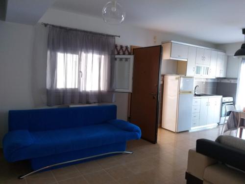 a living room with a blue couch and a kitchen at dimis apartment in Nea Michaniona