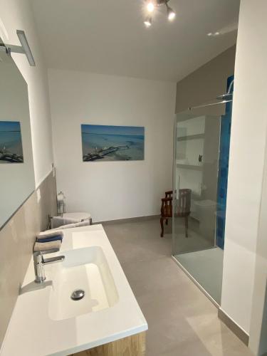 ein weißes Bad mit einem Waschbecken und einer Dusche in der Unterkunft Casa Linda in Porto Cesareo