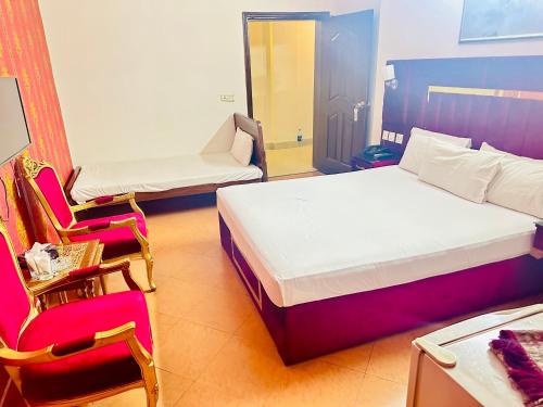 a room with a bed and a chair and a bed and a bed at Fiesta Inn Hotel & Resorts Multan in Multan