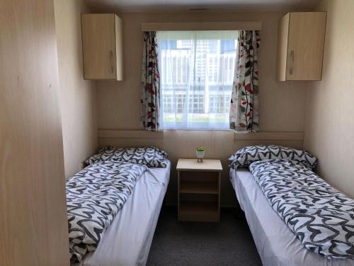 two beds in a small room with a window at Caravan on luxury Devon holiday park in Paignton