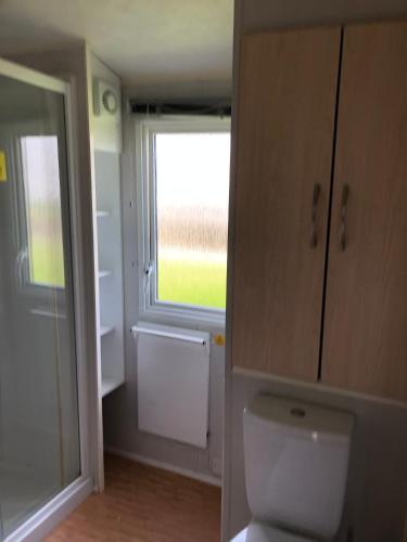 a bathroom with a toilet and a large window at Caravan on luxury Devon holiday park in Paignton