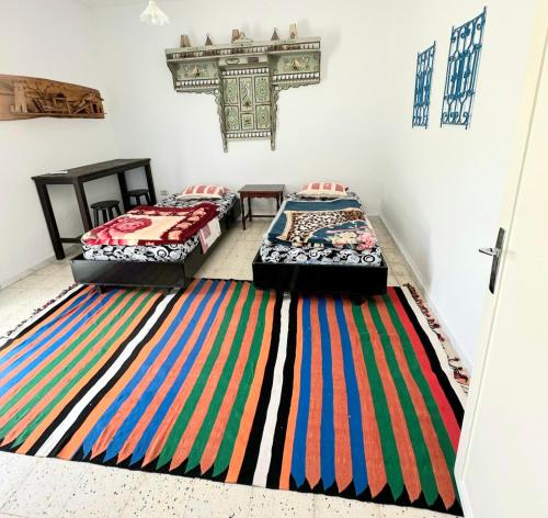 2 Betten in einem Zimmer mit farbenfrohem Teppich auf dem Boden in der Unterkunft Anis 2 in Sousse