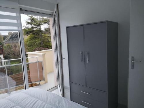 a bedroom with a dresser and a large window at Appartement St Cast, à 100m de la Grande Plage in Saint-Cast-le-Guildo