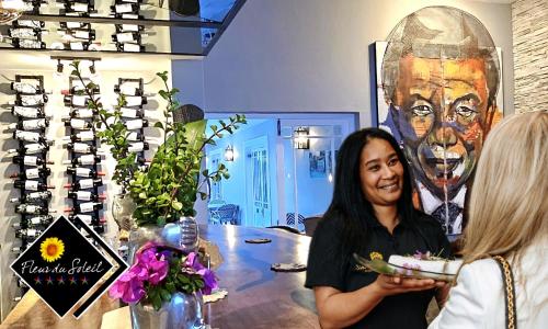 Fleur du Soleil Luxury Guesthouse في فرانستشوك: امرأة تمسك لوحة من الطعام في متجر