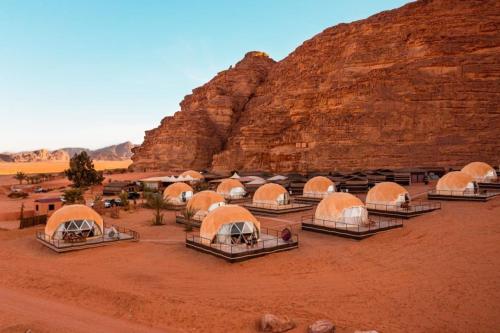 eine Gruppe von Zelten in der Wüste in der Nähe einer Klippe in der Unterkunft Hasan Zawaideh Camp in Wadi Rum