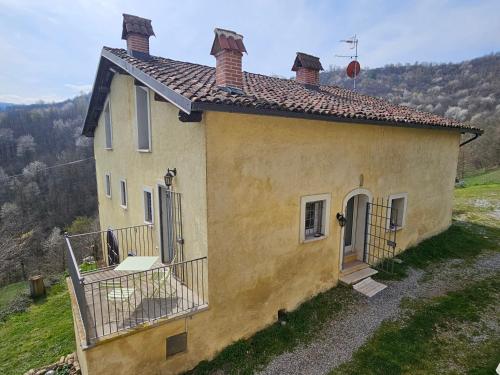 een klein geel huis bovenop een heuvel bij casa nel verde Cà dla cola in Mombasiglio