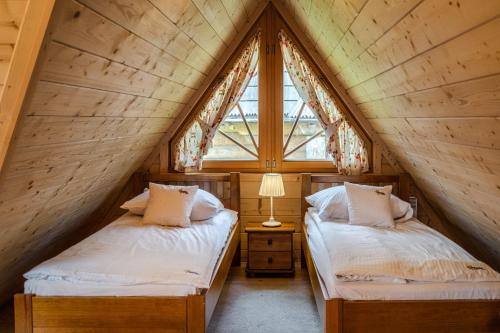 two beds in a attic bedroom with a window at Osada Kościelisko - Tatry na Wyciągnięcie Ręki in Kościelisko