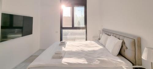 Cette chambre comprend un lit blanc et une télévision. dans l'établissement BnBIsrael apartments - Matmon Cohen Quartz, à Tel Aviv
