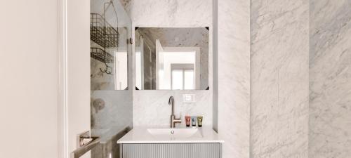 a white bathroom with a sink and a mirror at BnBIsrael apartments - Matmon Cohen Quartz in Tel Aviv