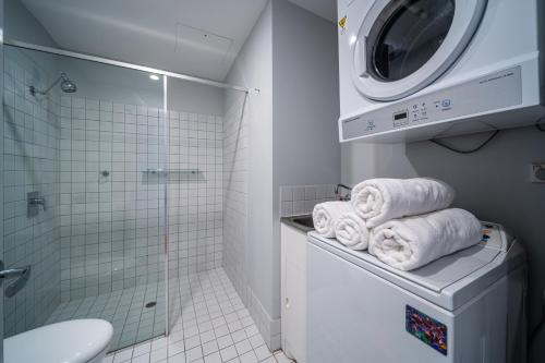 een witte badkamer met een wasmachine en handdoeken bij Paradiso on Bent Adelaide in Adelaide