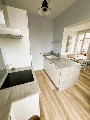 - une cuisine avec des placards blancs, un évier et une table dans l'établissement Appartement Cosy Villa Française, à Mers-les-Bains