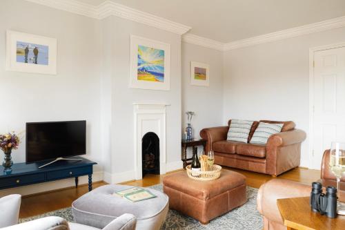 a living room with a couch and a tv at High View, Southwold High Street (2 bed, 2 bath, allocated parking, balcony) in Southwold