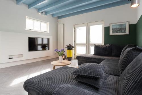 a living room with a couch and a tv at Pakhuis aan de Zaan in Wormerveer
