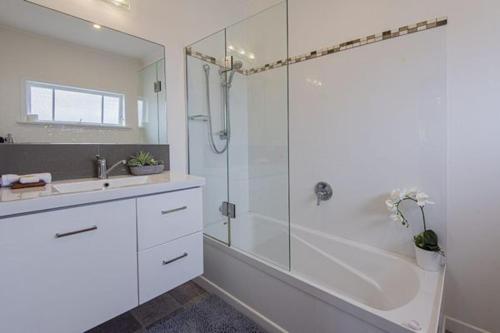 a white bathroom with a shower and a sink at Rest & Relax Villa Whangarei in Whangarei