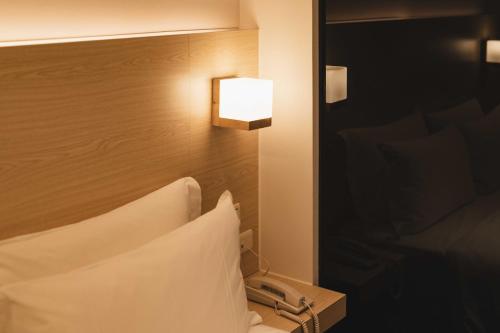 a hotel room with a bed with a light on the wall at SWIIO Hotel Ximending in Taipei