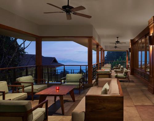 Taj Chia Kutir Resort & Spa Darjeeling في Kurseong: شرفة مع الأرائك والطاولات وإطلالة على المحيط