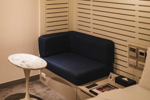 a blue couch in a room with a stool at SWIIO Hotel Ximending in Taipei
