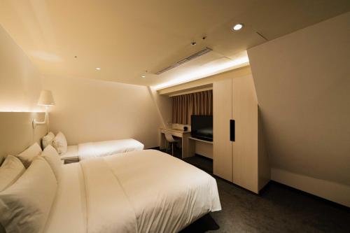 a hotel room with two beds and a desk at SWIIO Hotel Ximending in Taipei