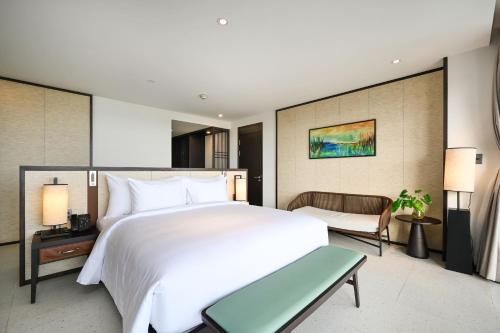 a bedroom with a large white bed and a chair at Emerald Ho Tram Resort in Ho Tram