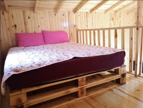 a bed in a wooden room with purple pillows at Şahan Bungalov in Gökçe