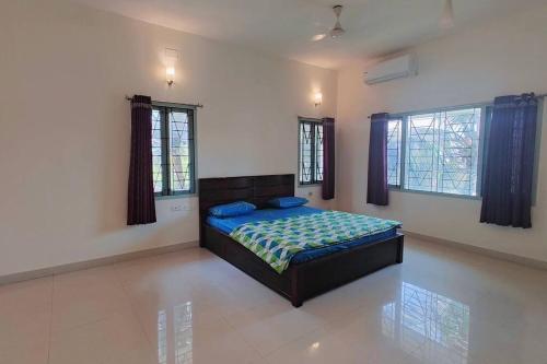 a bedroom with a bed in a room with windows at Shanthi Nivaas in Chennai