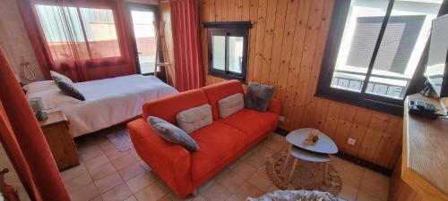 a living room with a red couch and a bed at La Forge du Rosay in Viry