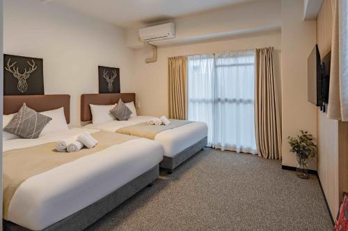 ein Hotelzimmer mit zwei Betten und einem Fenster in der Unterkunft b&通天閣店 in Osaka