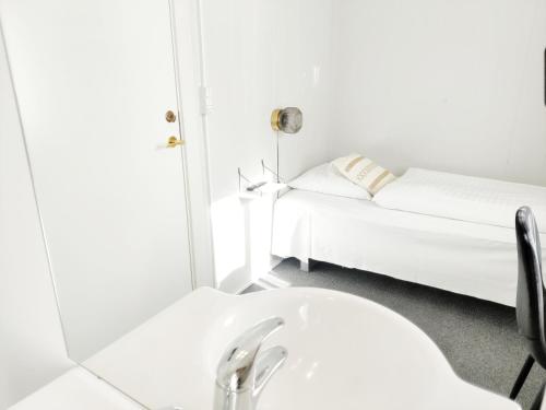 a white bathroom with a sink and a bed at CentralHotellet in Køge