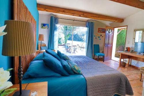 ein Schlafzimmer mit einem blauen Bett und einer Glasschiebetür in der Unterkunft Le Mas de Bertagne in Gémenos
