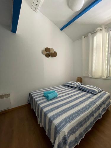 une chambre avec un lit avec une couverture rayée bleue et blanche dans l'établissement Appartement à 2 pas du Port de la Ciotat, à La Ciotat
