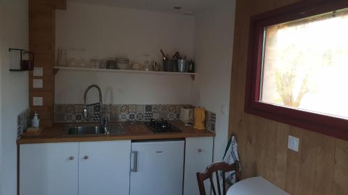 une petite cuisine avec un évier et une fenêtre dans l'établissement L 'Echo des bois, à Ambillou-Château