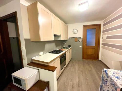 eine kleine Küche mit weißen Schränken und einer Mikrowelle in der Unterkunft Casa Nora in Manerba del Garda