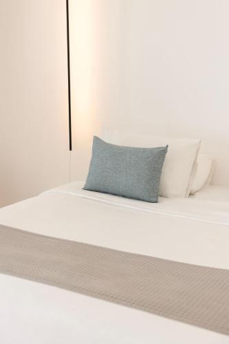 a white bed with a blue pillow on it at Zannos Luxury Suites By Zannos Collection in Pirgos