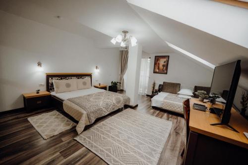 sypialnia z 2 łóżkami, biurkiem i telewizorem w obiekcie Pensiunea Paradisul Verde w mieście Oglinzi