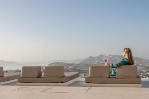 a woman sitting on a chair with a glass of wine at Zannos Luxury Suites By Zannos Collection in Pirgos