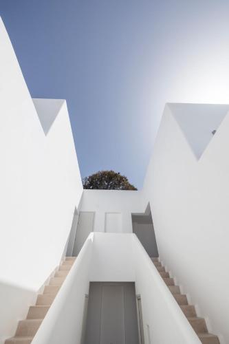 a staircase in a white building with a potted plant at Zannos Luxury Suites By Zannos Collection in Pirgos