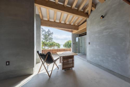 a room with a chair and a table and a window at Amami 与庵 in Amami