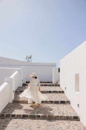 a woman in a white dress walking down stairs at Zannos Luxury Suites By Zannos Collection in Pirgos