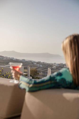 a woman sitting on a couch looking out of a window at Zannos Luxury Suites By Zannos Collection in Pirgos