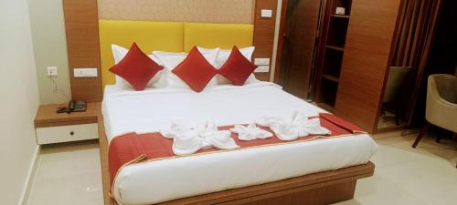 a bedroom with a bed with red pillows and white shoes at HOTEL ORCHID VISTA in Tirupati