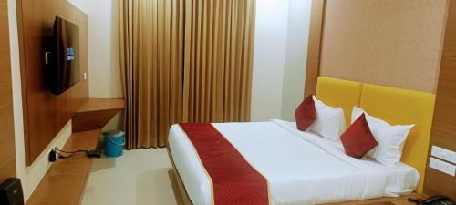蒂魯帕蒂的住宿－HOTEL ORCHID VISTA，一间卧室配有带白色床单和红色枕头的床。