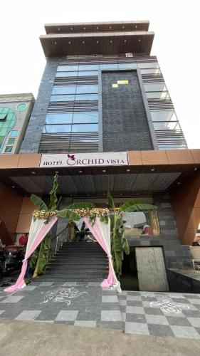 un edificio alto con sombrillas rosas delante en HOTEL ORCHID VISTA, en Tirupati