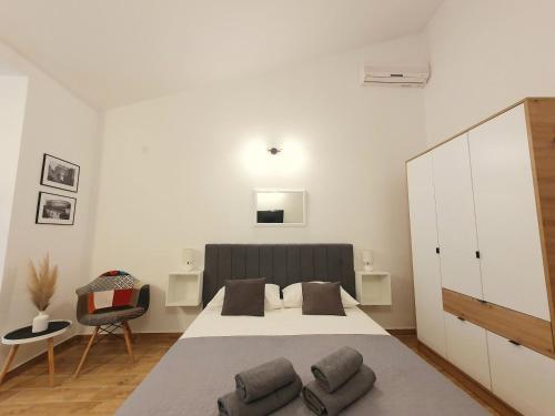 a white bedroom with a large bed and a chair at Apartments Dejana Štinjan in Štinjan