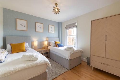 a bedroom with two beds and a dresser at High View, Southwold High Street (2 bed, 2 bath, allocated parking, balcony) in Southwold