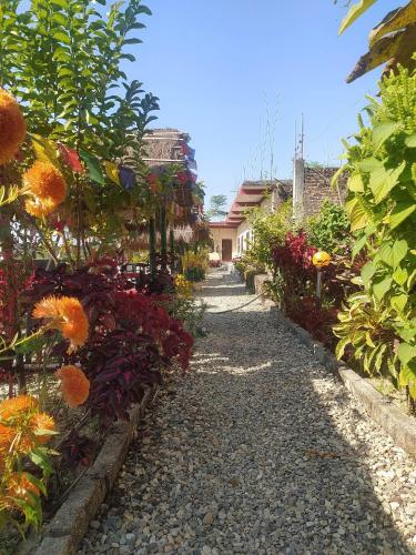 a garden with flowers on a gravel road at Busy Bee Guest House in Sauraha